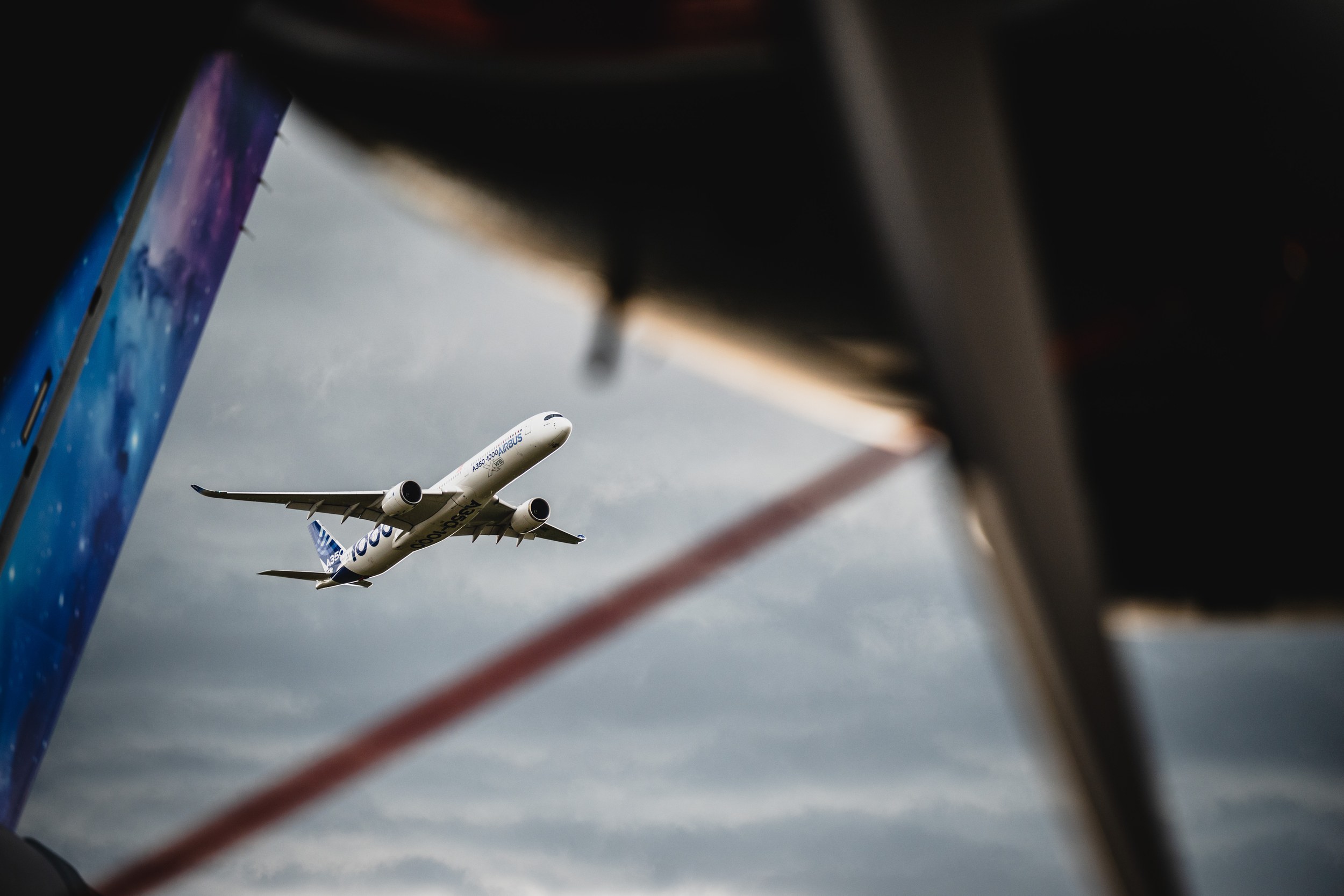 An Airbus A350-1000 in Airbus demonstration livery climbs during the Flying Display against a grey clouded sky. Large da