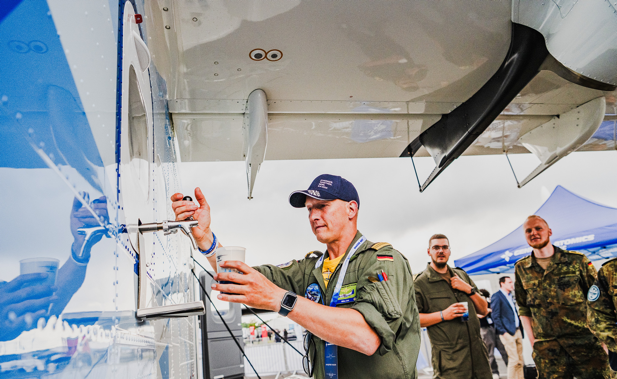Pilot taps a drink at the bar under the wing of the Do228 NXT